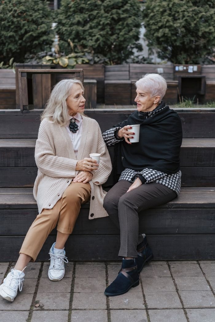 Two women having a quiet conversation on a bench